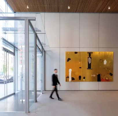 a man is walking through a lobby with a large painting on the wall .