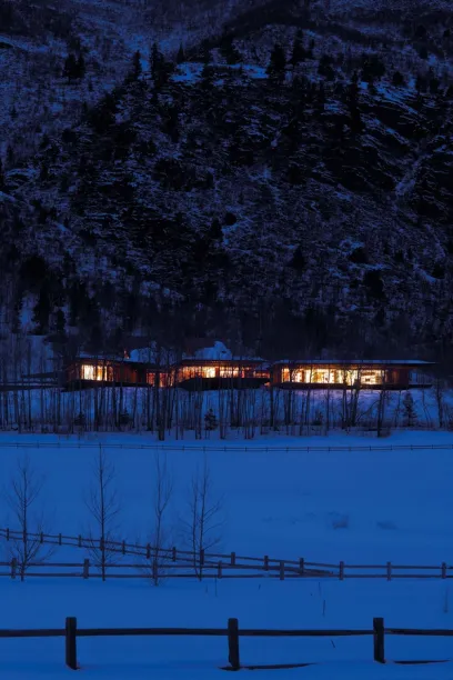 A snowy field with a fence and a house in the background