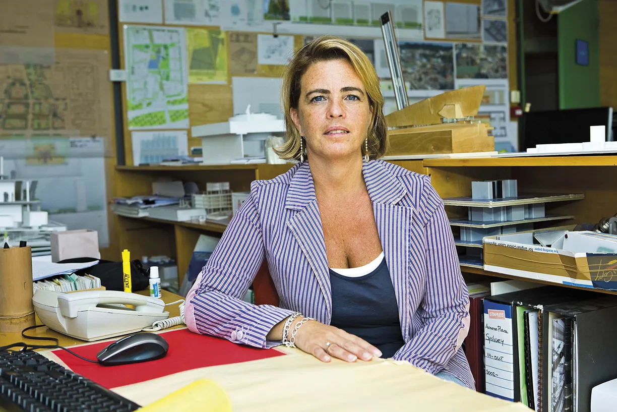 A woman in a striped jacket sits at a desk