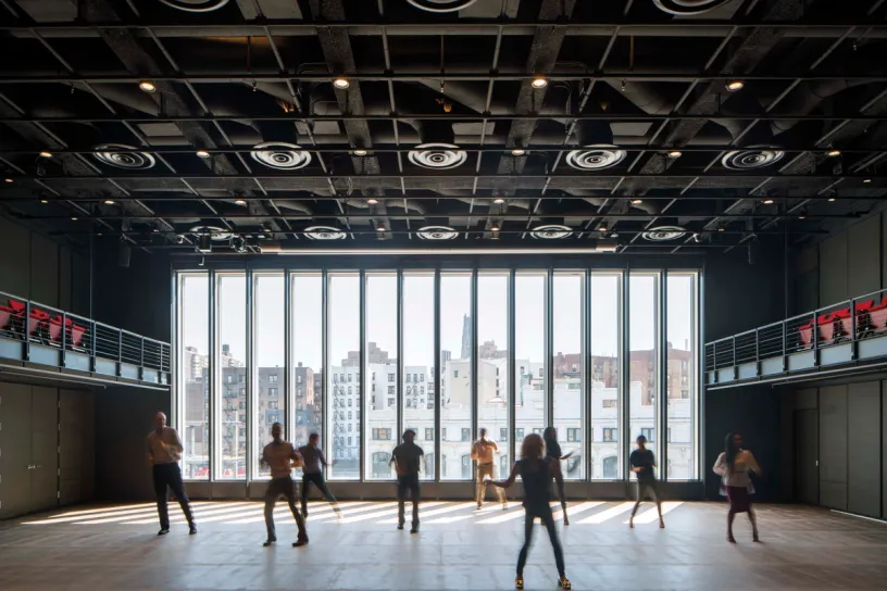 a woman is walking in front of a large window with a view of a city .