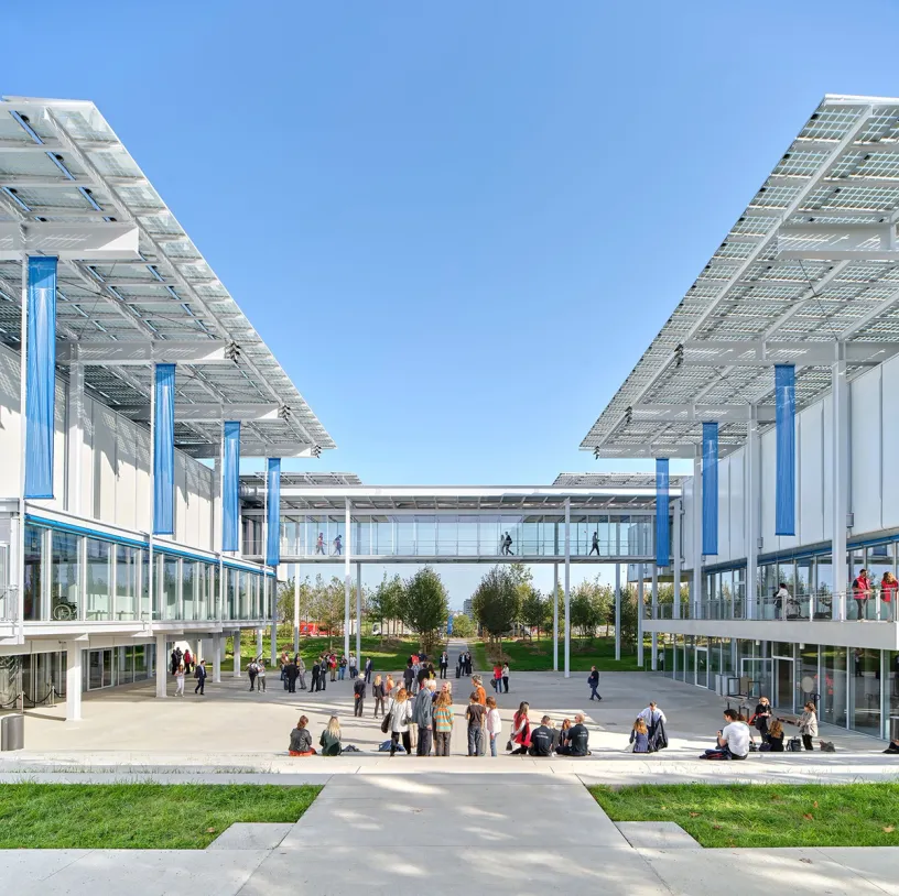 A group of people are sitting on the sidewalk in front of a large building
