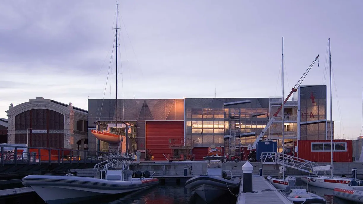 a group of boats are docked in front of a building in a harbor .