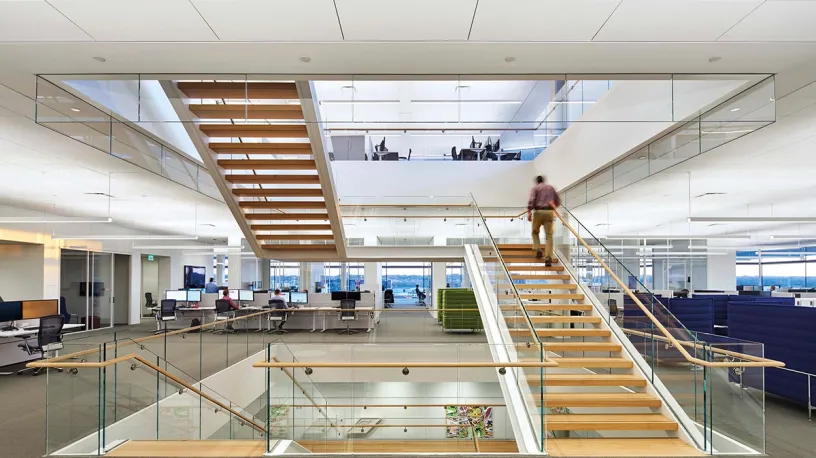 A man is walking up a set of stairs in an office building