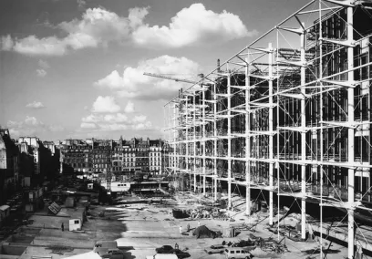 A black and white photo of a large building under construction in a city