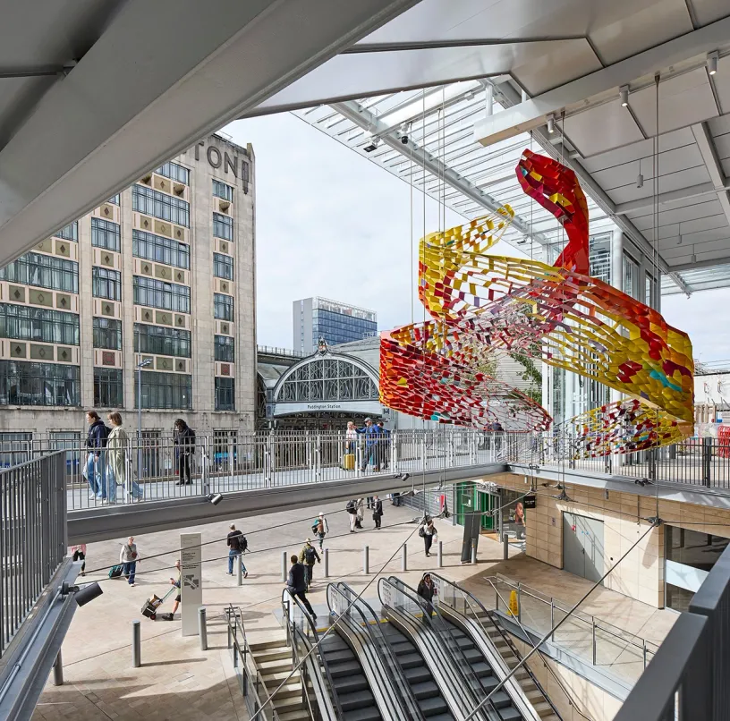 A large colorful sculpture is hanging from the ceiling of a building