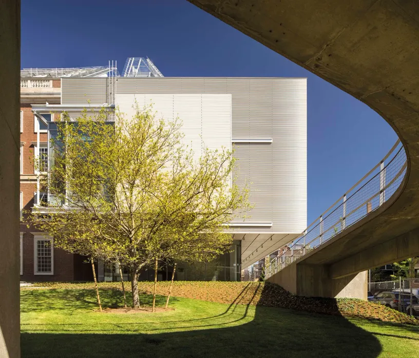 A large white building with a bridge and trees in front of it