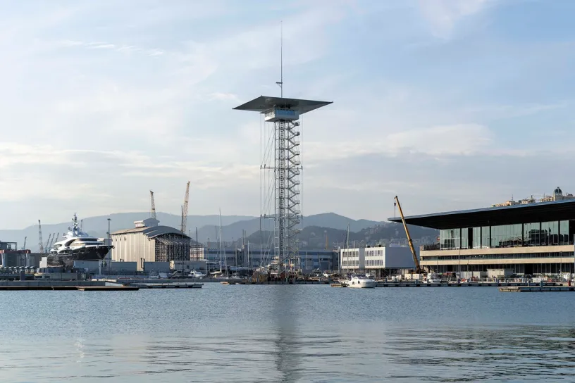 A large tower in the middle of a harbor with boats in the water
