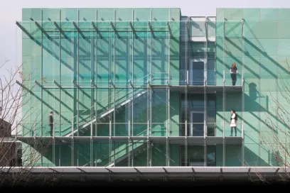 A woman is standing on the balcony of a building with a glass facade