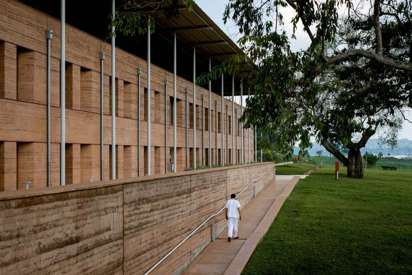 A man is walking down a ramp towards a large building