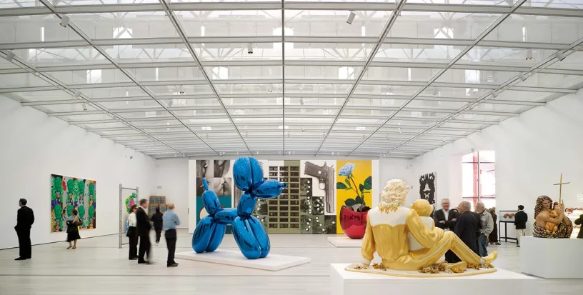 A group of people are standing in a museum looking at sculptures