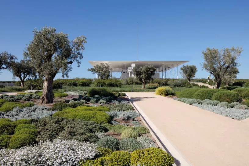 a path leading to a large building surrounded by trees and bushes .