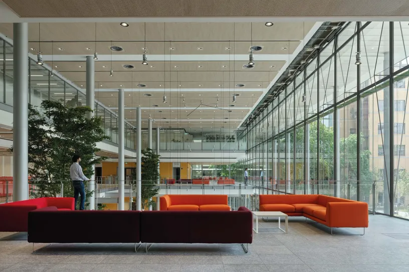 A man is standing in a lobby of a large building with orange couches