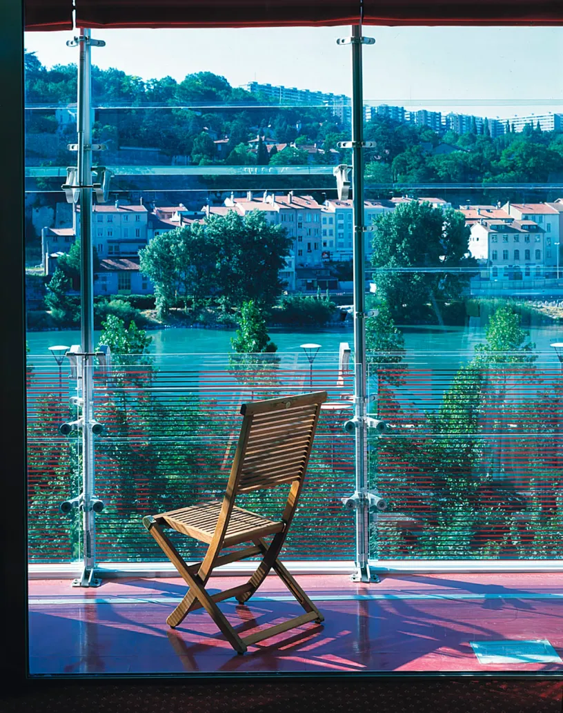 A chair sits in front of a window overlooking a river