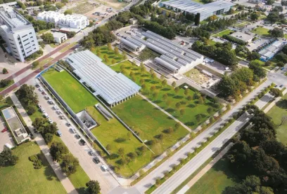 An aerial view of a large building with a green roof in a city