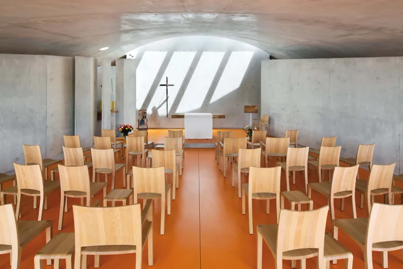A church with wooden chairs and a cross on the altar