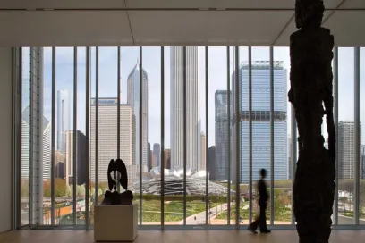A statue is standing in front of a large window with a view of the city skyline