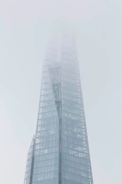 A tall building with a lot of windows is covered in fog