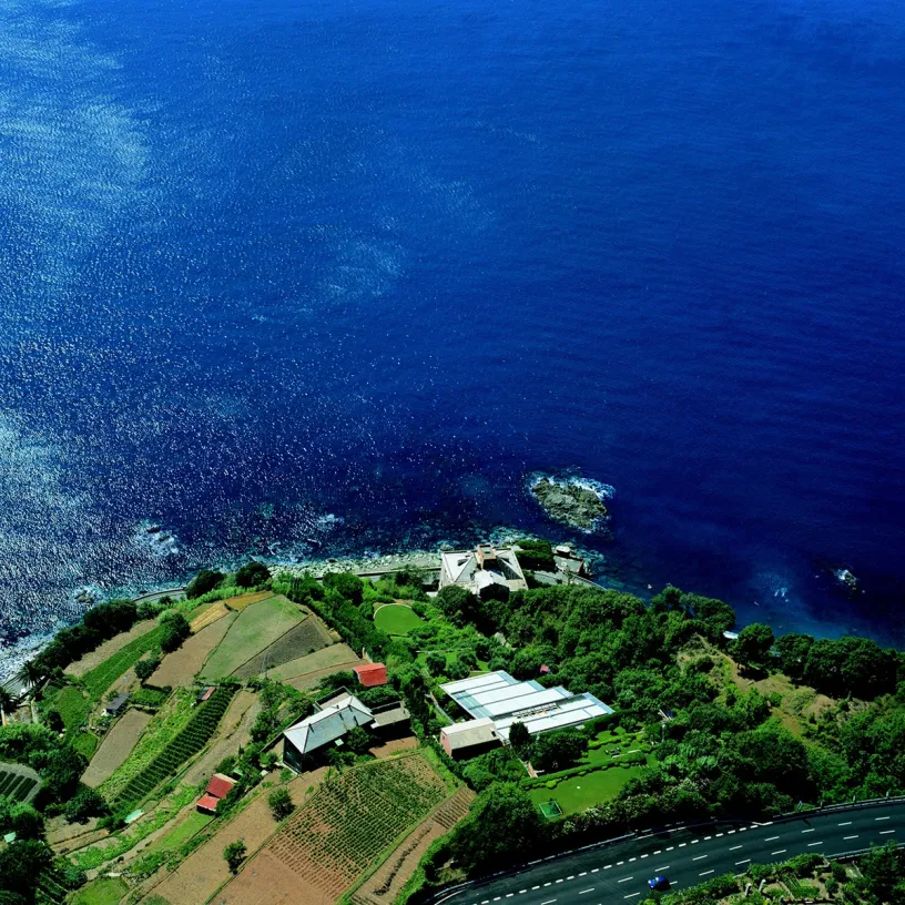 An aerial view of a house on a hill near the ocean
