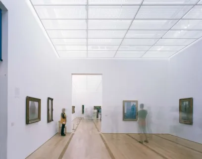 A woman is standing in a museum looking at paintings