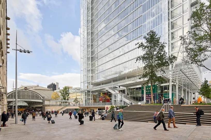A group of people are walking in front of a tall building