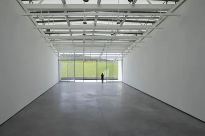 A man is standing in a large empty room with a large window