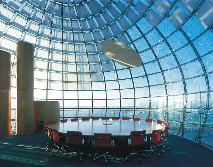 A conference room with a round table and chairs under a glass dome