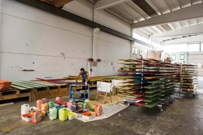 a man is painting a piece of wood in a warehouse .
