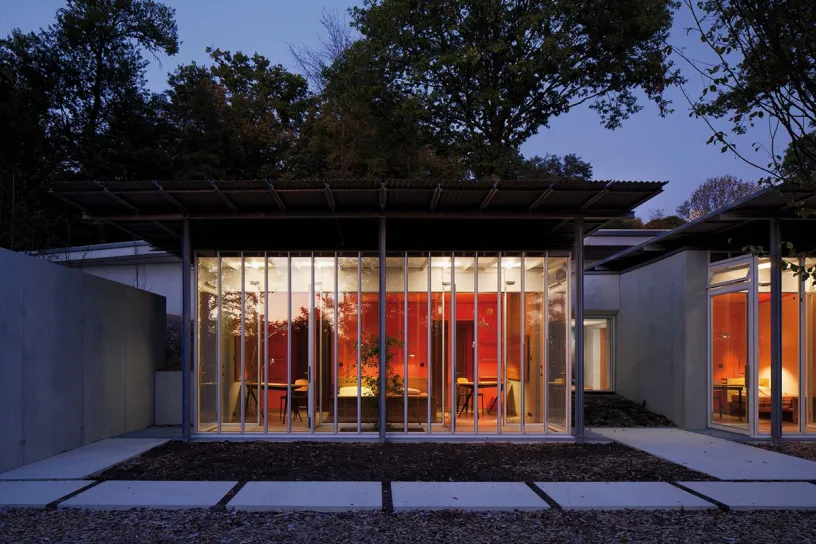 A modern house with a lot of windows and trees in the background at night