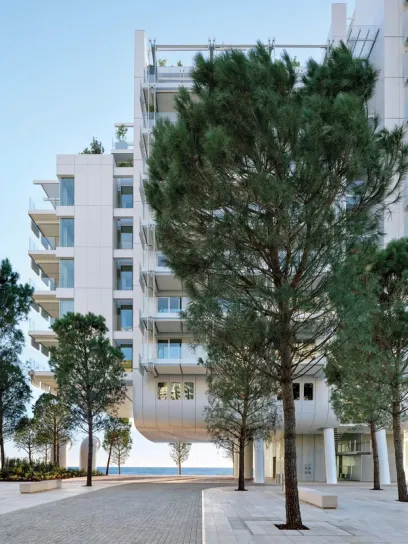 A large white building with balconies and trees in front of it