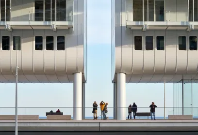A group of people are standing on a balcony of a building overlooking the ocean