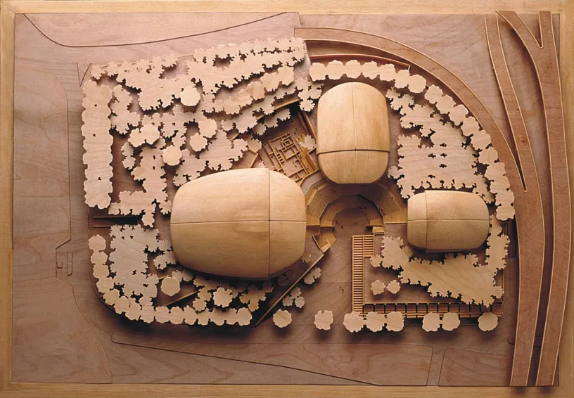 A wooden model of a building with trees around it