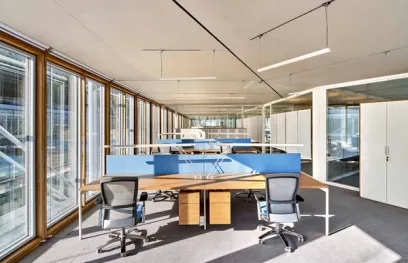 a large office with lots of windows and desks and chairs .