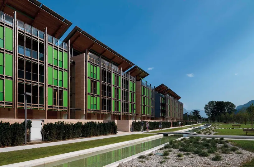 a large building with green windows and a pond in front of it .