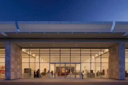 A group of people are standing in front of a large glass building
