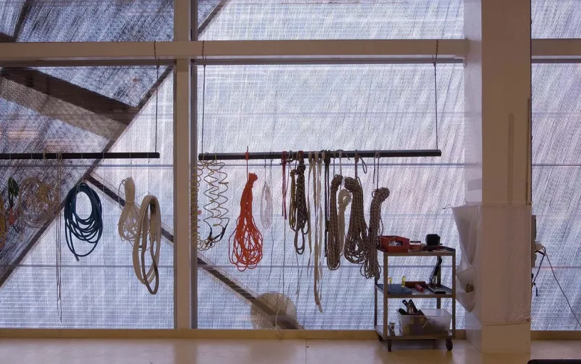 a bunch of ropes are hanging from the ceiling in a room .