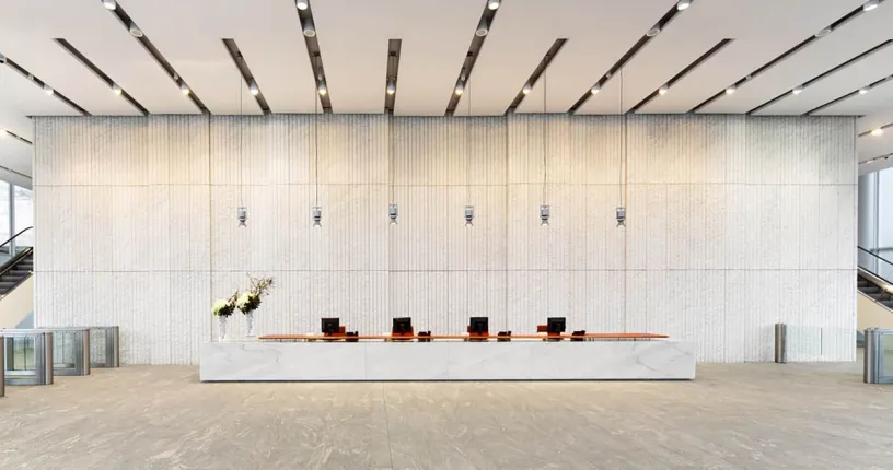 A large lobby with a long marble counter and stairs