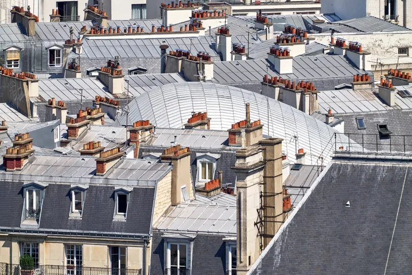There are many chimneys on the roofs of buildings in paris