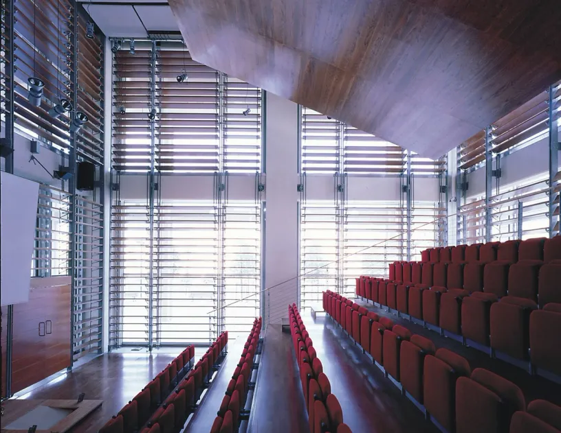 A large auditorium with red seats and a lot of windows