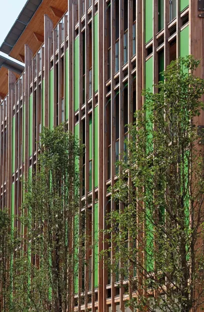 a building with green shutters and trees in front of it