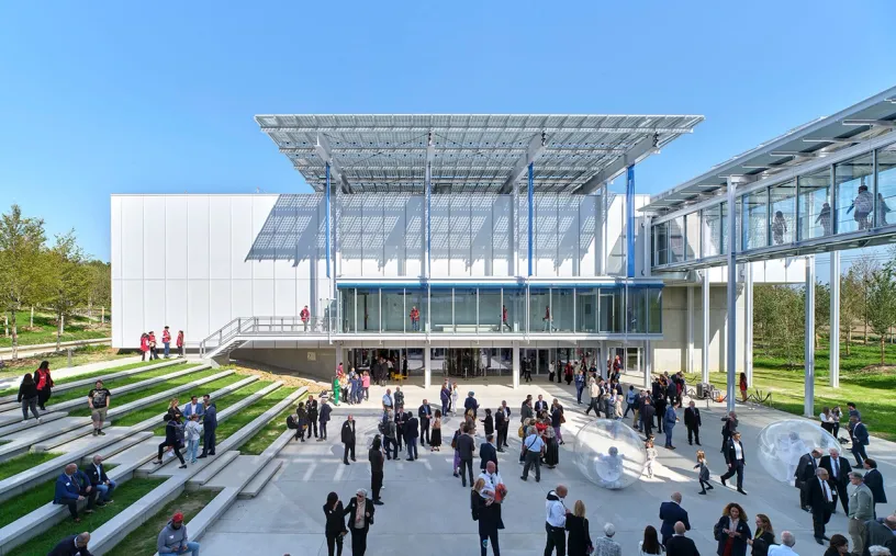 A large group of people are standing in front of a large building