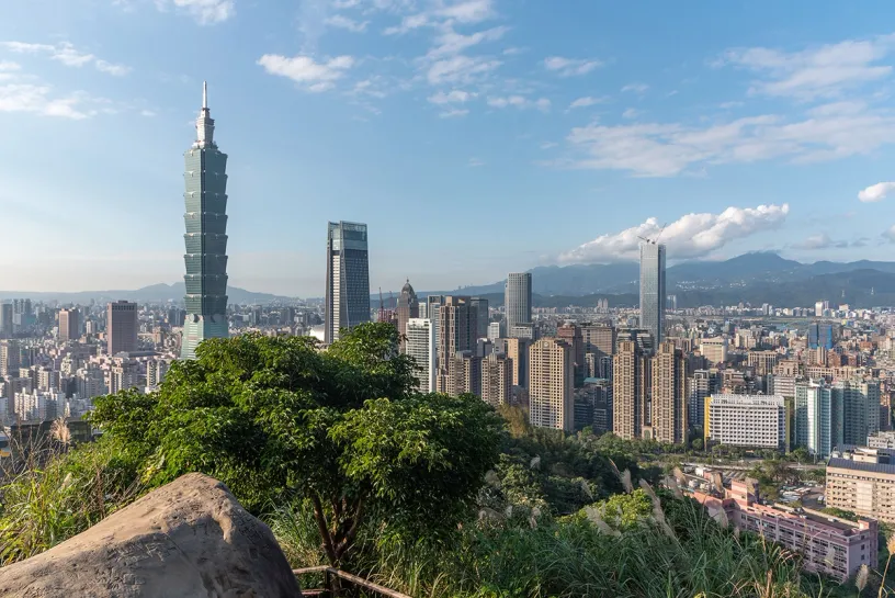 A view of a city from a hill with mountains in the background