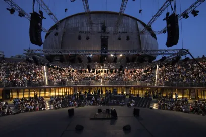 A large crowd of people are sitting in a large stadium at night