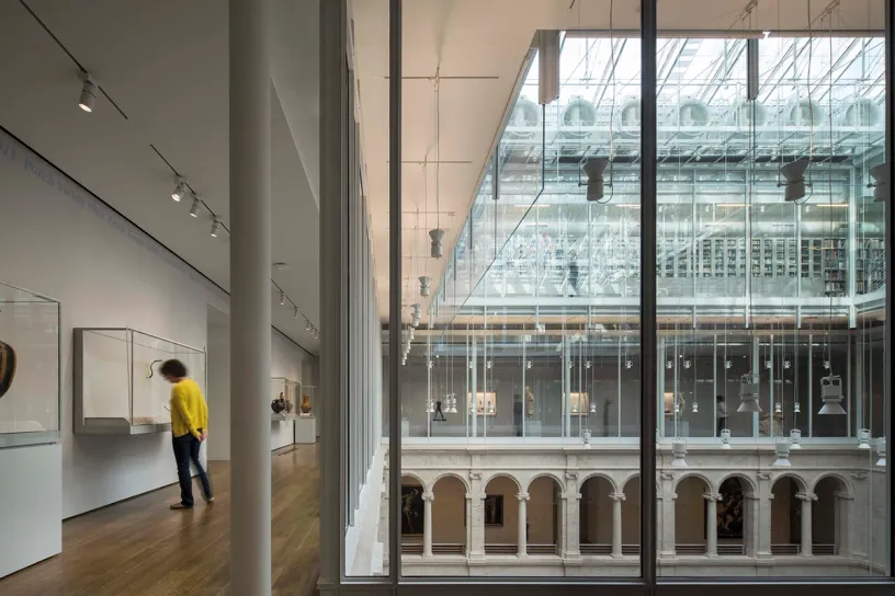 A woman is standing in a museum looking out of a large window