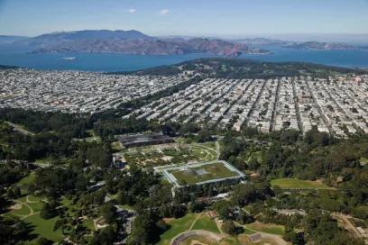 an aerial view of a city and a park with mountains in the background .