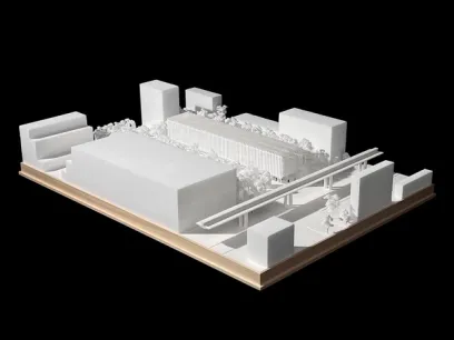 White architectural model of an urban development featuring multiple buildings, an elevated track, and trees.