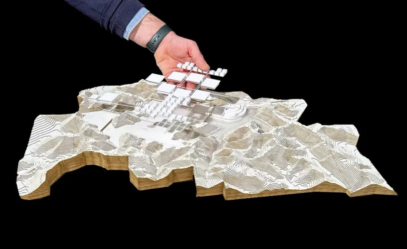 A person is holding a model of a city on a black background