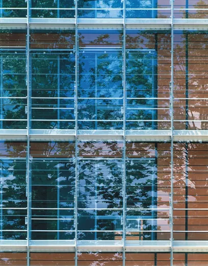 A building with a lot of windows and trees reflected in them