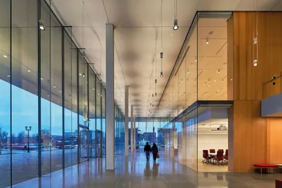 A couple of people are walking down a long hallway in a building