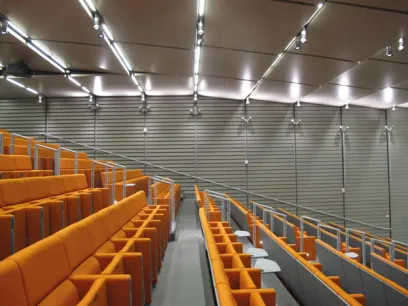 There are rows of orange seats in a large auditorium
