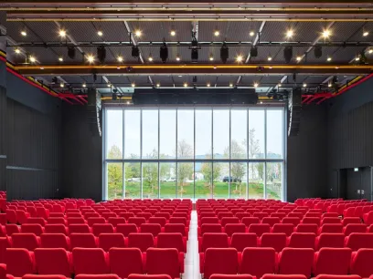 A large auditorium filled with red seats and a large window